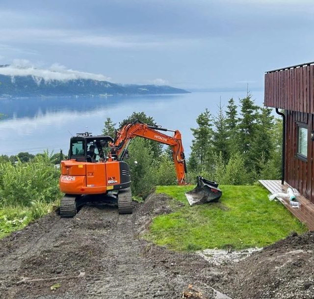 Liten gravemaskin i arbeid utenfor hus